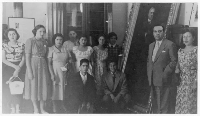 Grupo de mujeres y tres hombres alrededor de un cuadro