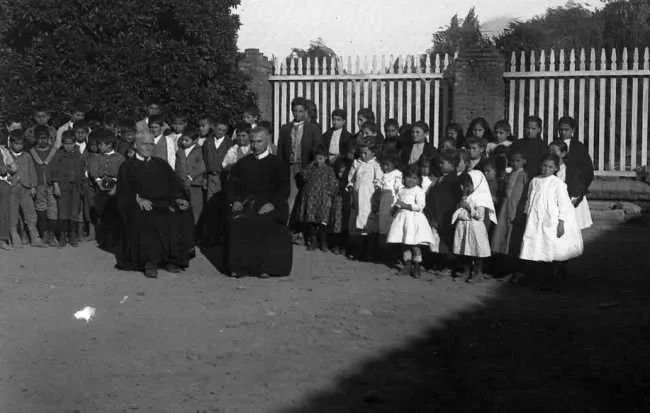 Niños en Torno a Dos Sacerdotes