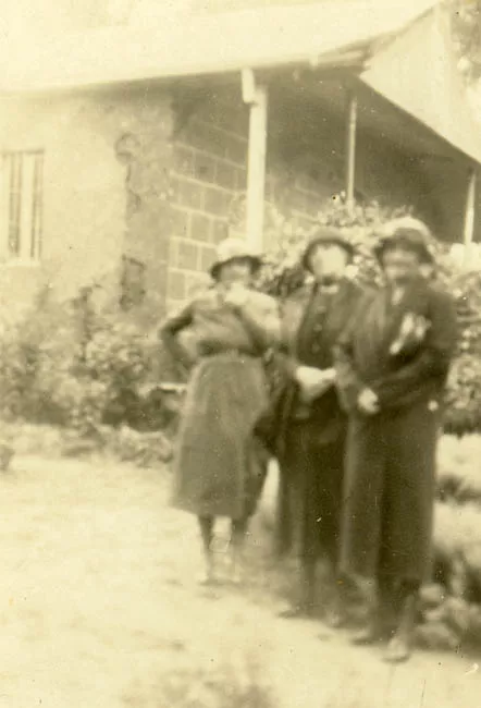 Tres damas frente a la entrada de una casa