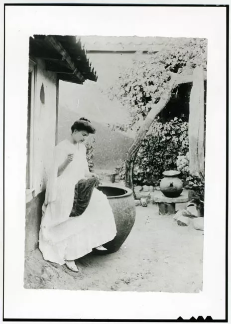 Mujer cosiendo en casona colonial
