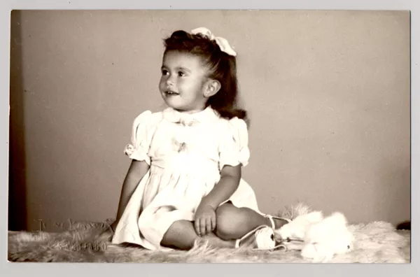 [ Niña de vestido blanco veraniego y cinta en el pelo sentada sobre un felpudo]  [fotografía] Kyutaro Tunekawa.