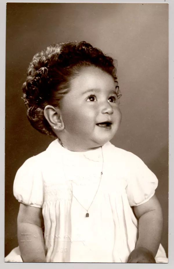 [Niñita de pelo rizado peinado hacia atrás vestido blanco mangas cortas y una cadena colgando en el cuello]  [fotografía] Kyutaro Tunekawa.