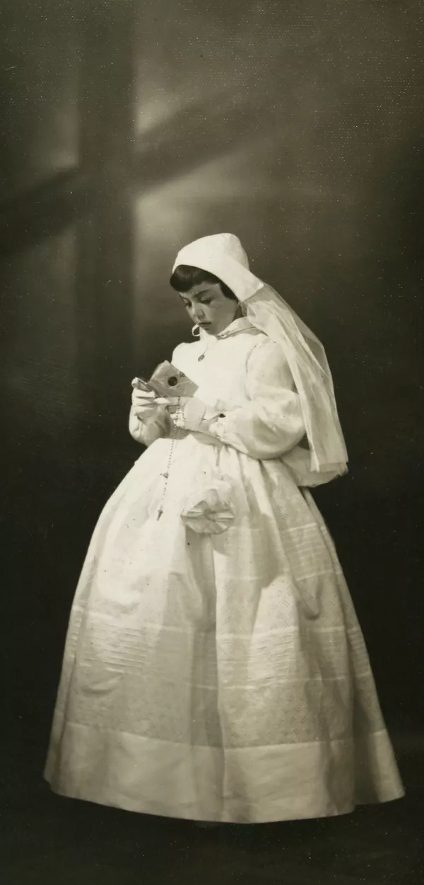 [Niña de Primera Comunión con guantes blancos y una toca con velo hata la cintura]  [fotografía] Kyutaro Tunekawa.