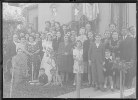 [Novios posando con un gran número de familiares y amigos en el jardín de la casa]  [fotografía]Kyutaro Tunekawa.