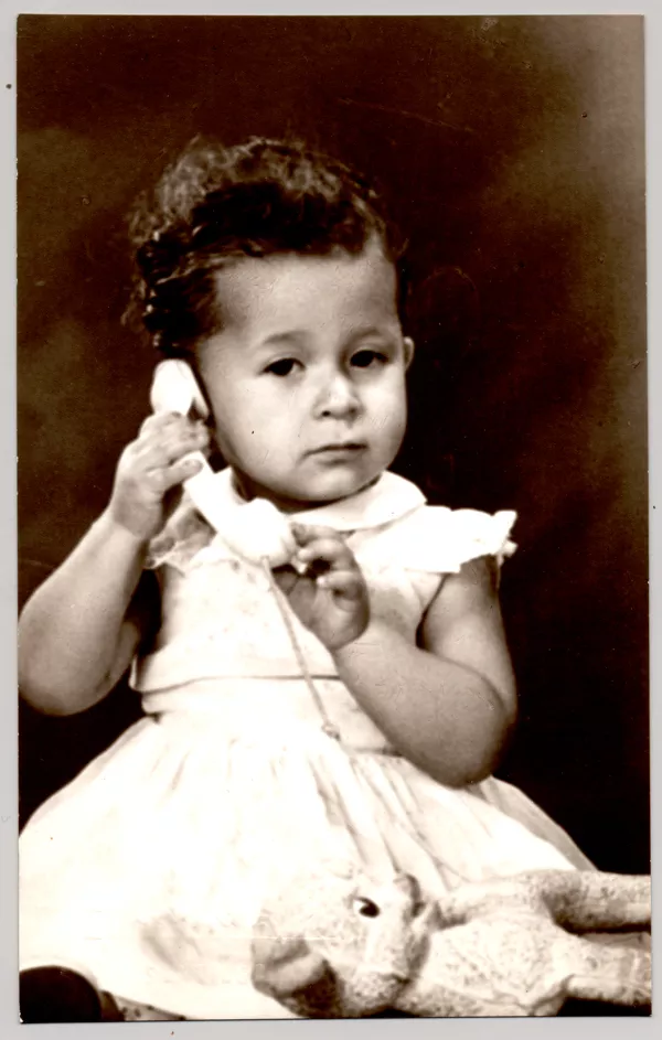 [Niñita de pelo corto ondulado, vestido blanco amplio, hablando por teléfono]  [fotografía] Kyutaro Tunekawa.