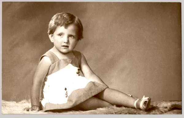 [Niñita rubia sentada de lado con las piernas cruzadas, vestido de dos colores y chalas blancas]  [fotografía] Kyutaro Tunekawa.