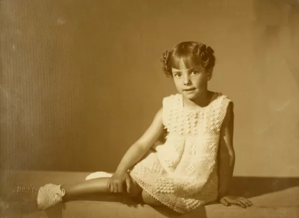 [Niñita rubia de vestido color blanco de hilo grueso y zaptillas blancas, sentada con las piernas hacia el lado]  [fotografía] Kyutaro Tunekawa.