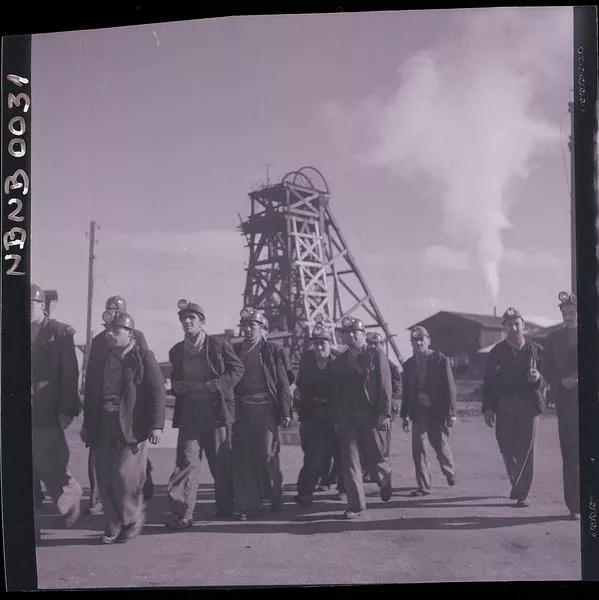 [Grupo de mineros en el exterior de la mina, tras ellos, torre de perforación de los pozos mineros]  [fotografía] Ignacio Hochhäusler.