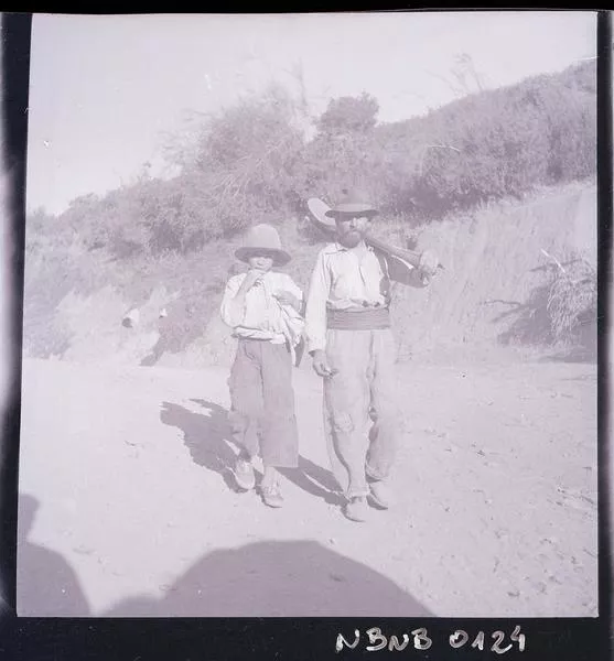 [Campesino con pala al hombro camina junto a su hijo]  [fotografía] Ignacio Hochhäusler.