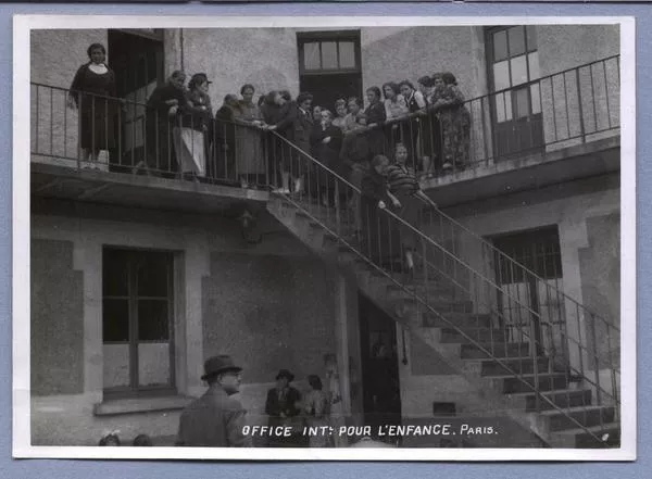 [Refugiadas españolas en baranda de un segundo piso, otras bajando por escalas exteriores, en campo refugiados de Dammarie, Francia]  [fotografía].