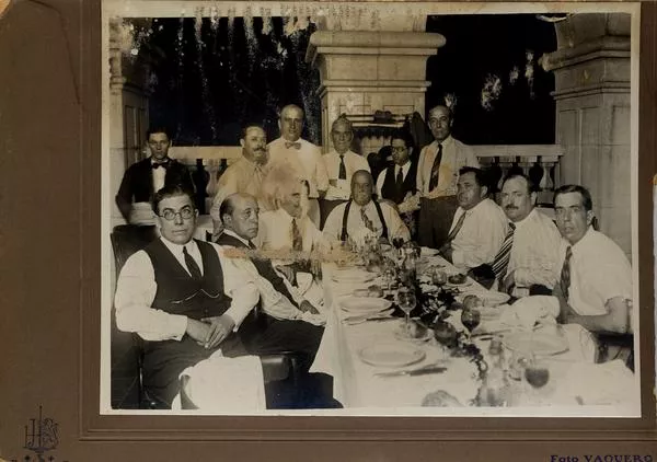[Grupo de hombres no identificados comparten una cena]  [fotografía] Foto Vaquero.