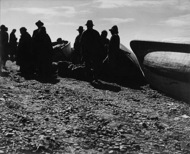 [grupo de personas a orillas de playa, esperan embarcación para transportar sus productos]  [fotografía] Jorge Opazo Galindo.