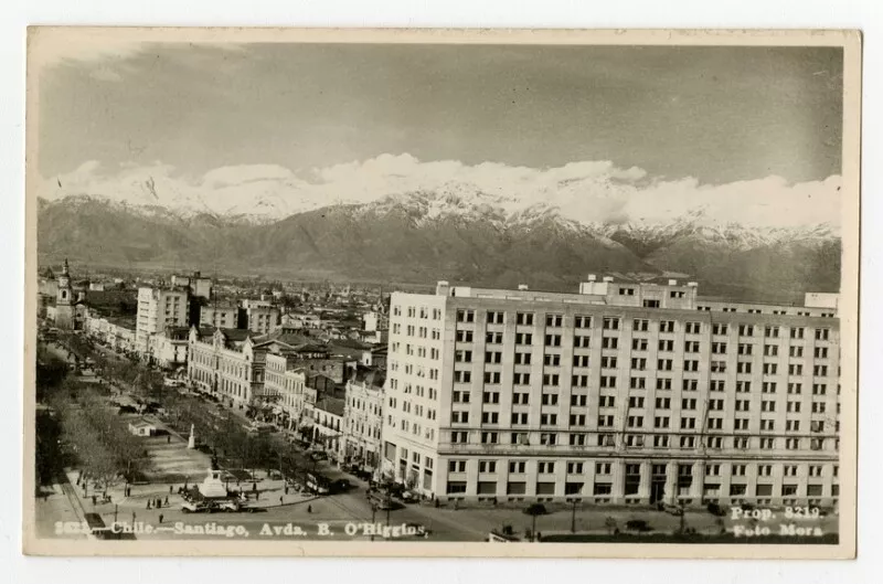 Chile, Santiago; Avda. B.O'Higgins : [Barrio Cívico: vereda sur; edificio del Ministerio de Defensa (Calle Zenteno N° 45), Casa Central de la Universidad de Chile, entre otros edificios, en último plano, la Iglesia San Francisco. En el bandejón central, se ubican monumentos, entre ellos el del General Manuel Bulnes; Como telón de fondo, la Cordillera de Los Andes] [fotografía] Foto Mora.