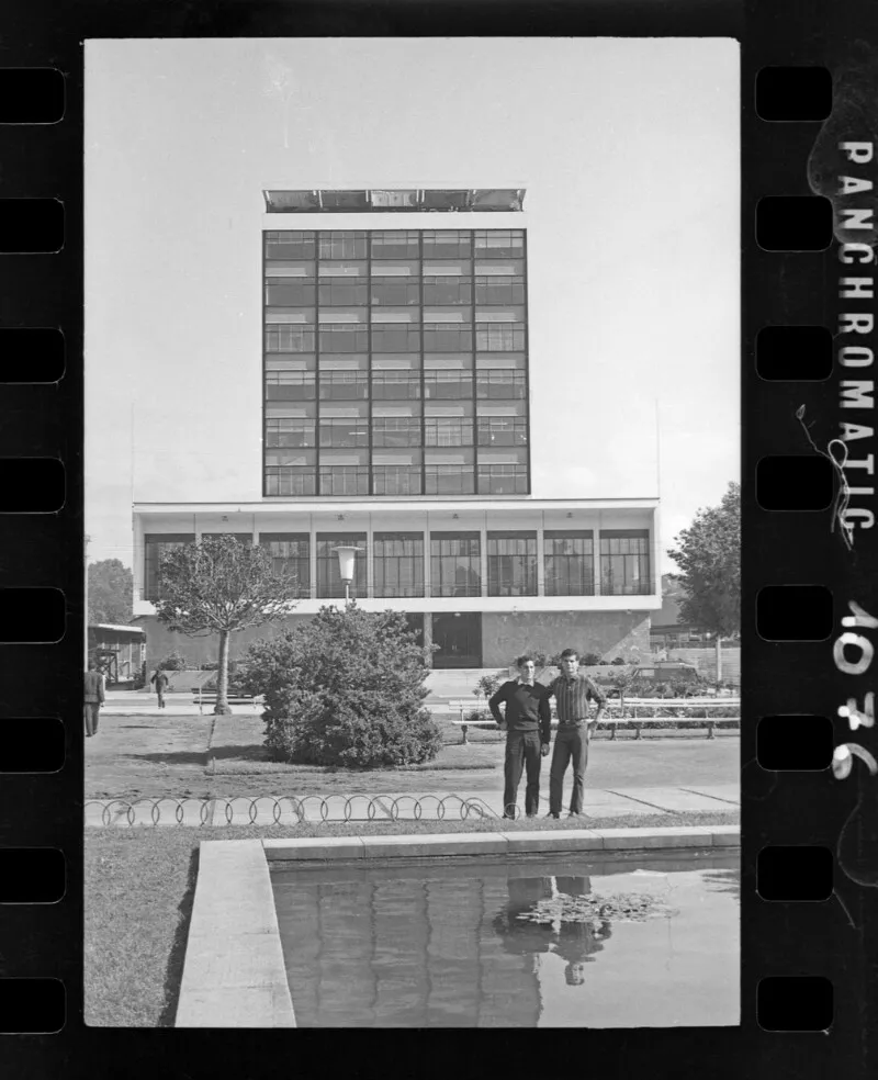 [Dos jóvenes frente a edificio]  [fotografía] Antonio Quintana.