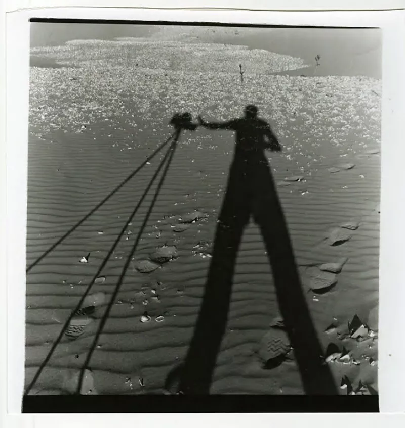 [Silueta del fotógrafo y su cámara en la arena, iluminación natural]  [fotografía] Bob Borowicz.