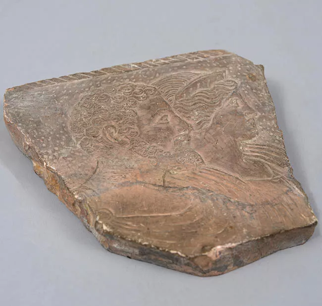 Trozo de mármol rosa con dos cabezas en relieve