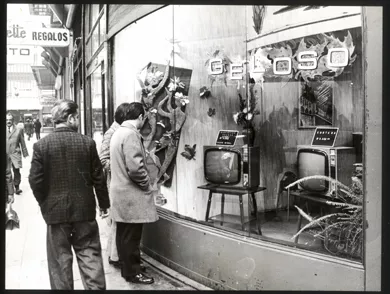 Peatones mirando una vitrina de televisores