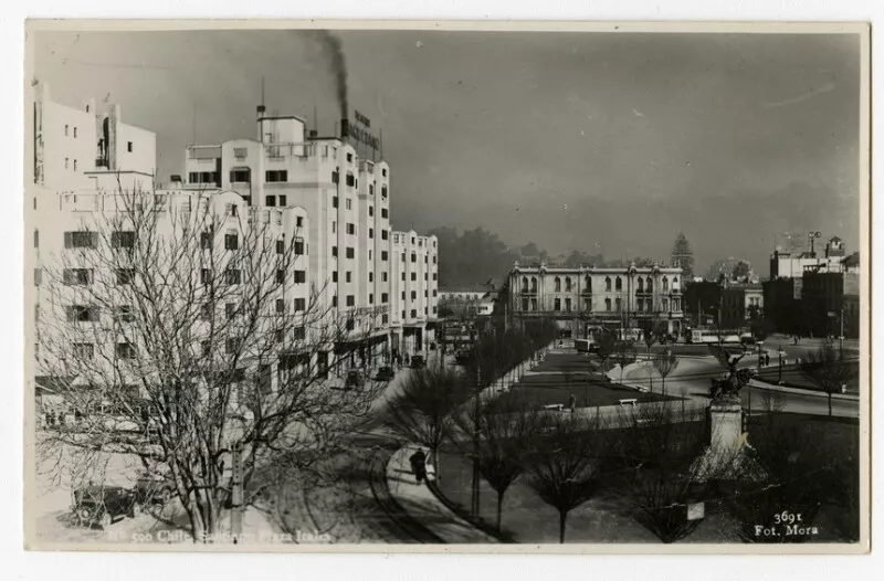 Chile, Santiago, Plaza Italia : ["Monumento al Genio de la Libertad" (Arcángel alado junto a un león), donacion de la Colonia Italiana con motivo del Centenario; vista del Teatro Baquedano, ubicado en los edificios Turri, anuncia "El Enemigo Público. Edificio Nieto, esquina sur poniente de la Plaza, en la planta baja se ubican locales comerciales; en segundo plano, se observa el Cerro San Cristóbal y la Virgen] [fotografía]